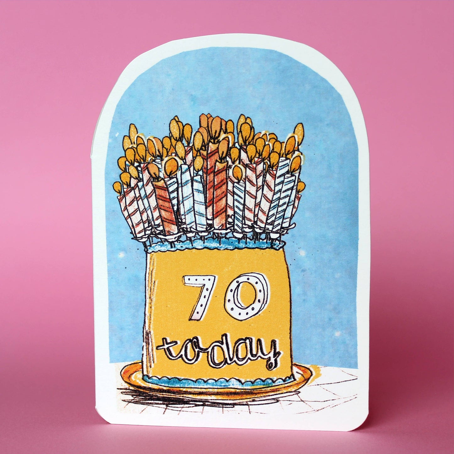 Whimsical 70th birthday card featuring a yellow birthday cake with candles and '70 Today' text on a pale blue background. Designed by Laura Skillbeck, handmade in the UK from recycled card.