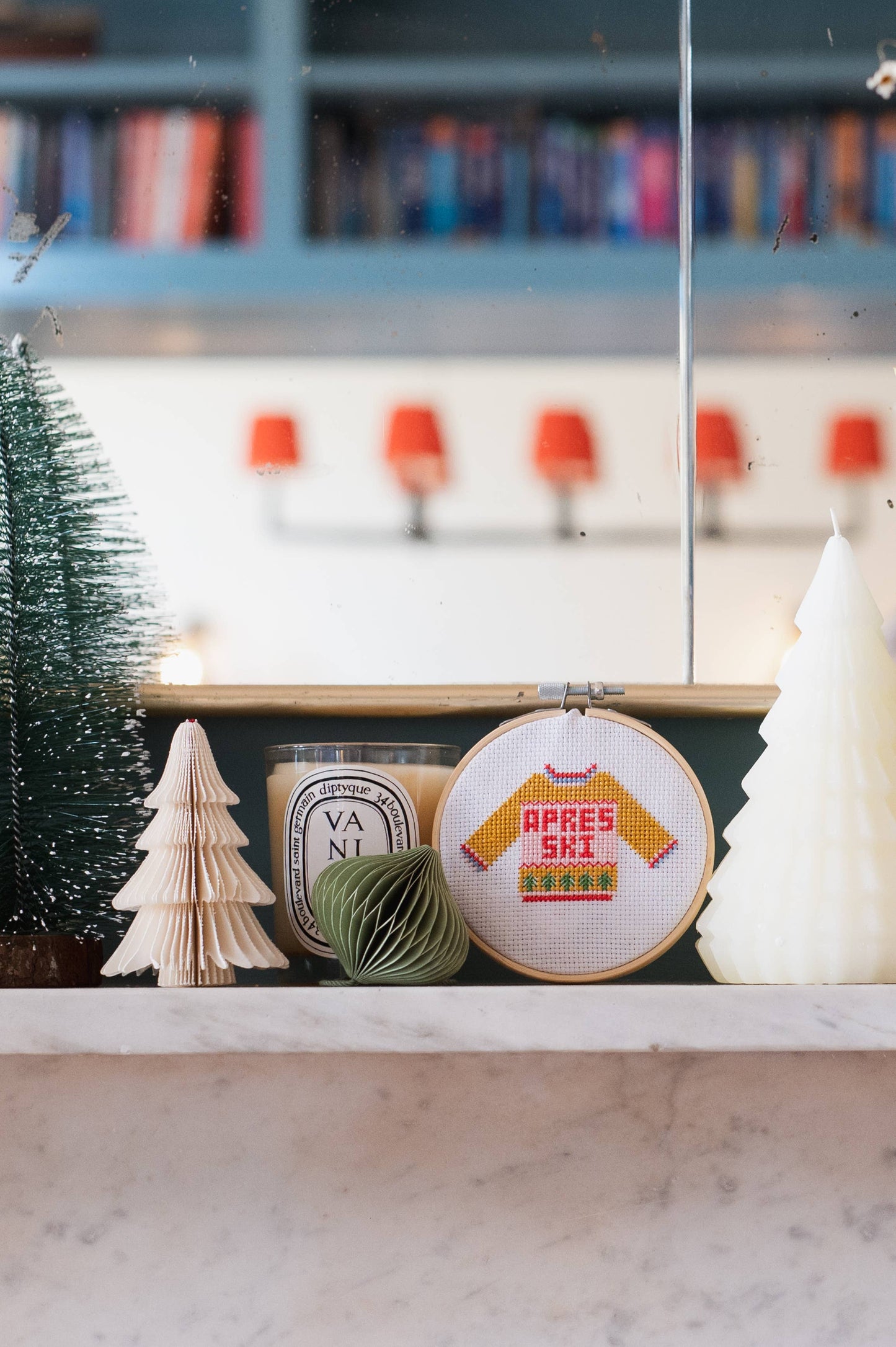 Completed Apres Ski Jumper Cross Stitch displayed on a festive mantelpiece with other Christmas decorations, showing it in a home setting.