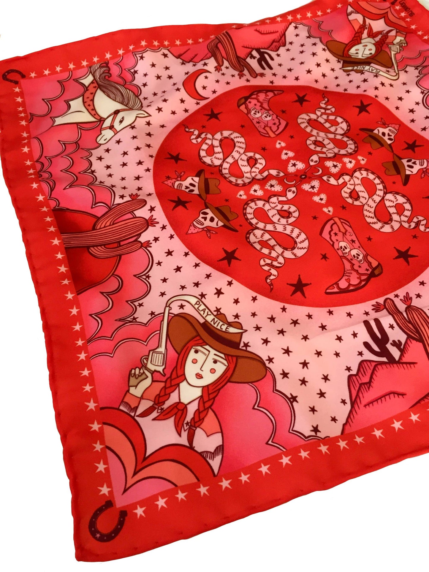 Eco silk twill pocket square with sassy cowgirl and white stallion, cacti, stars, boots, snakes, mountains, and horseshoe border in red and pink. Made from recycled polyester, designed by Su Owen.