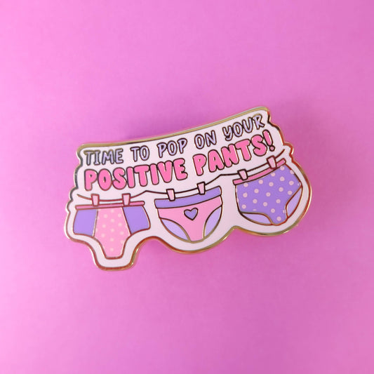 Close up of pink and purple Positive Pants enamel pin