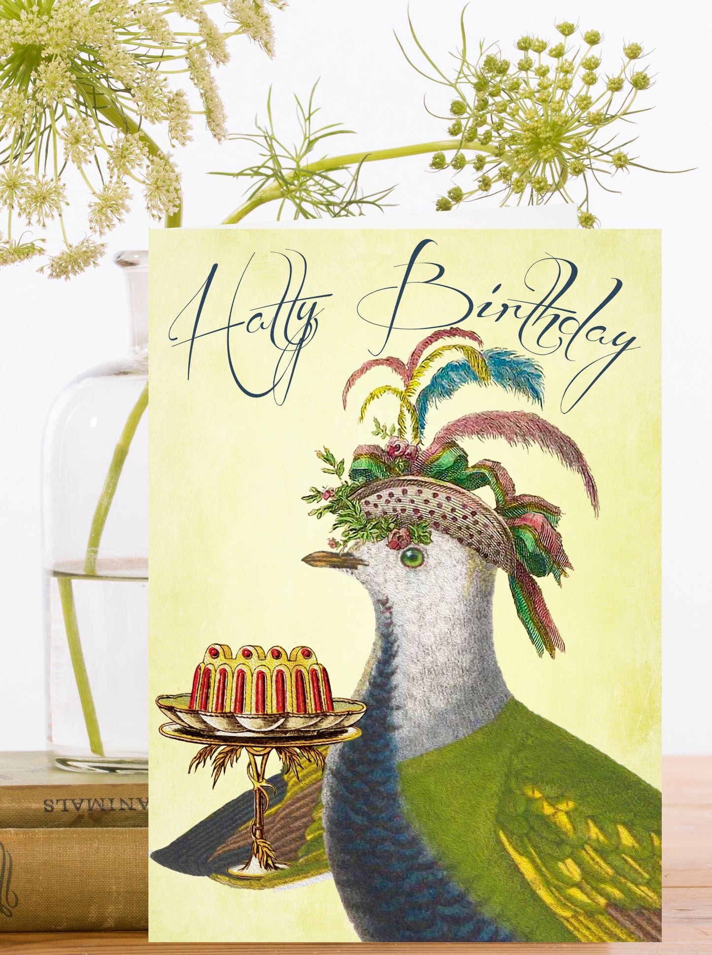Sustainable Birdie Birthday Greeting Card. A dapper pigeon in a fancy hat presents a cake with 'Hatty Birthday' text. Eco-friendly, vintage design.