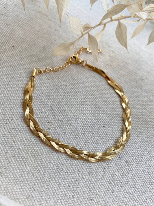 Lifestyle shot of the 18k gold plated braided snake chain bracelet stacked with other jewellery