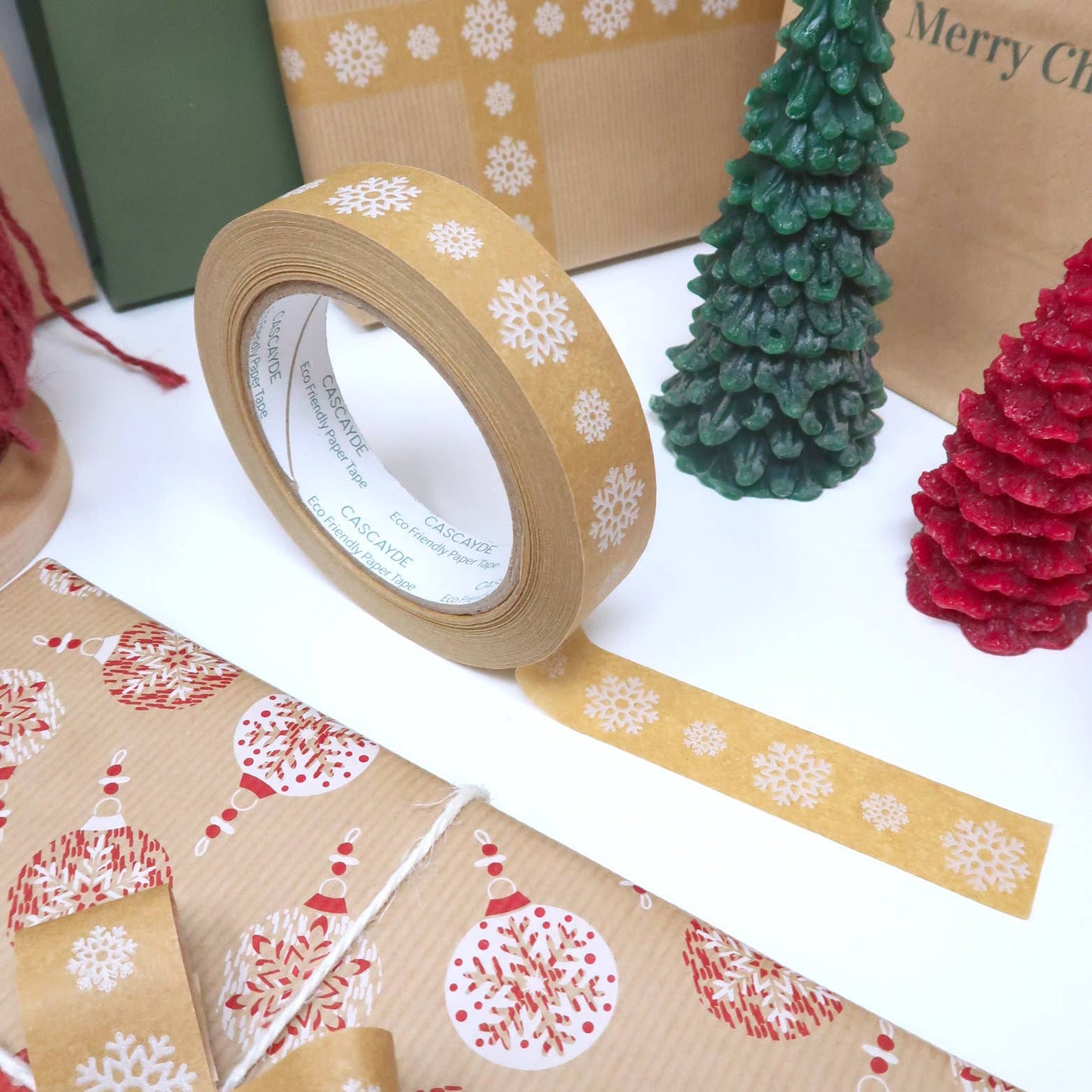 Roll of eco-friendly brown kraft paper tape with white snowflake design, 24mm wide, suitable for Christmas gift wrapping and crafting.