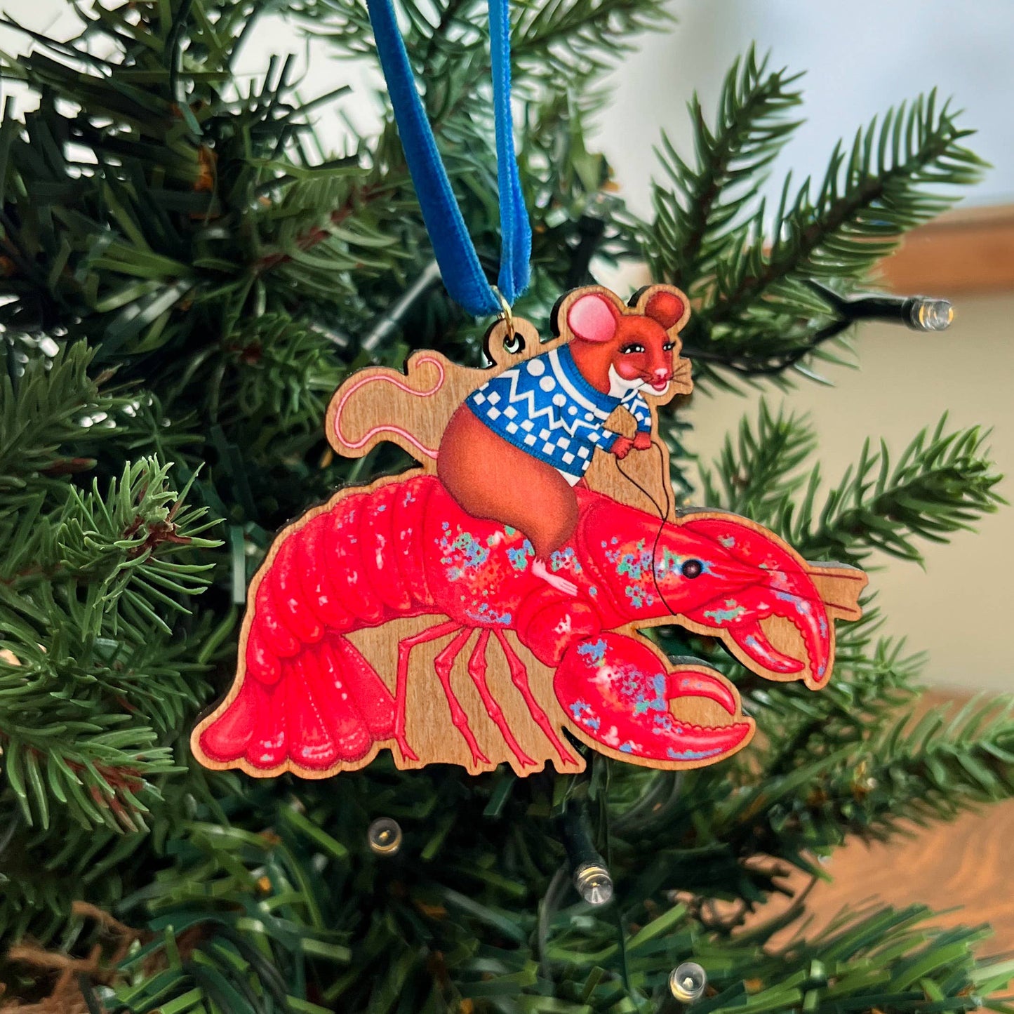 Mouse On A Lobster wooden Christmas tree decoration with Teddy & Kipling illustration, sustainably certified cherry wood, gold-plated ring, and royal blue velvet ribbon.