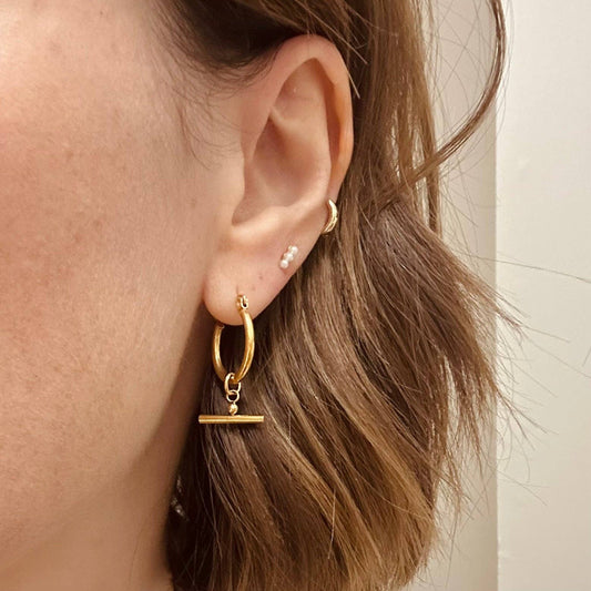 Model wearing Little Nell Gold Bar Hoops, showcasing their elegant drop and charm