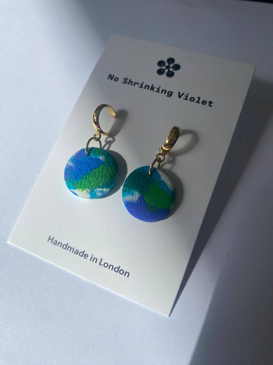 Close-up of small round pastel coloured dangle earrings