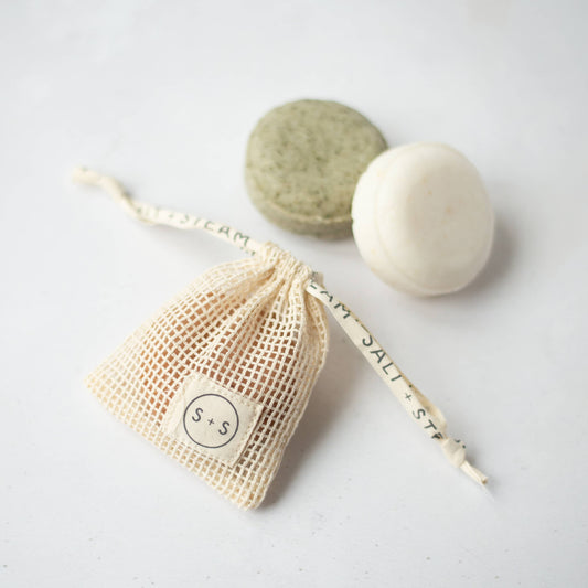 Eco-friendly natural cotton pouch holding a solid shampoo bar, air-drying