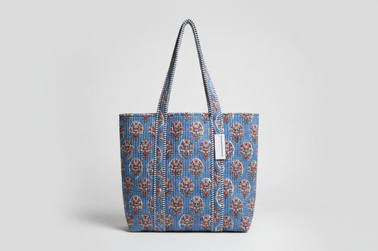 Blue patterned bag with a strap on a white cabinet background