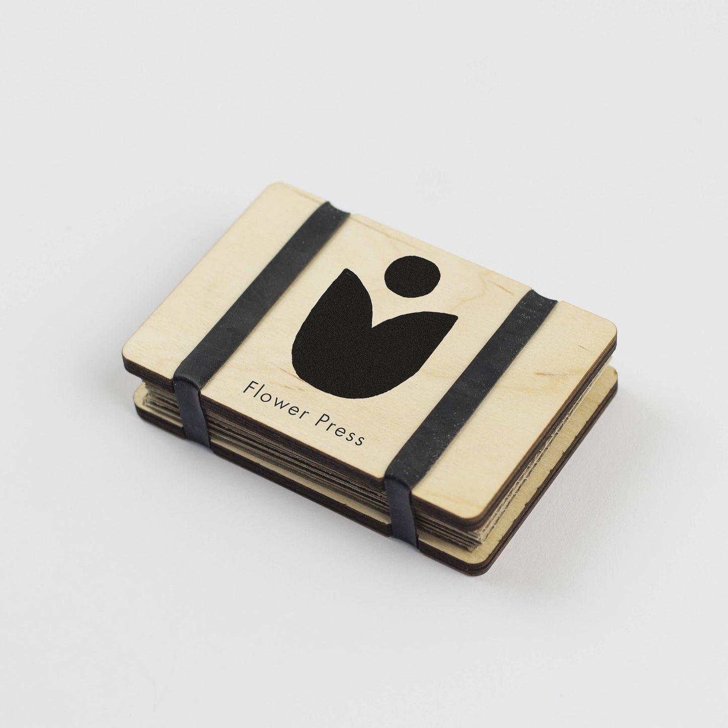 Pocket Size Flower press by Studio Wald. Black and white images of flowers on maple veneered sustainably sourced wood. Made in the UK. Fasten using the elastic bands and pop the press in your pocket. - The press comes complete with 5 sheets of corrugated card and 8 of sugar paper to give ample space to press flowers.