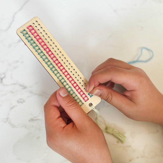 Child stitching wooden bookmark from craft kit