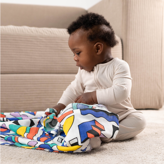 Baby enjoying tummy time on Etta Loves Walala 'Shapes' organic muslin, promoting visual development