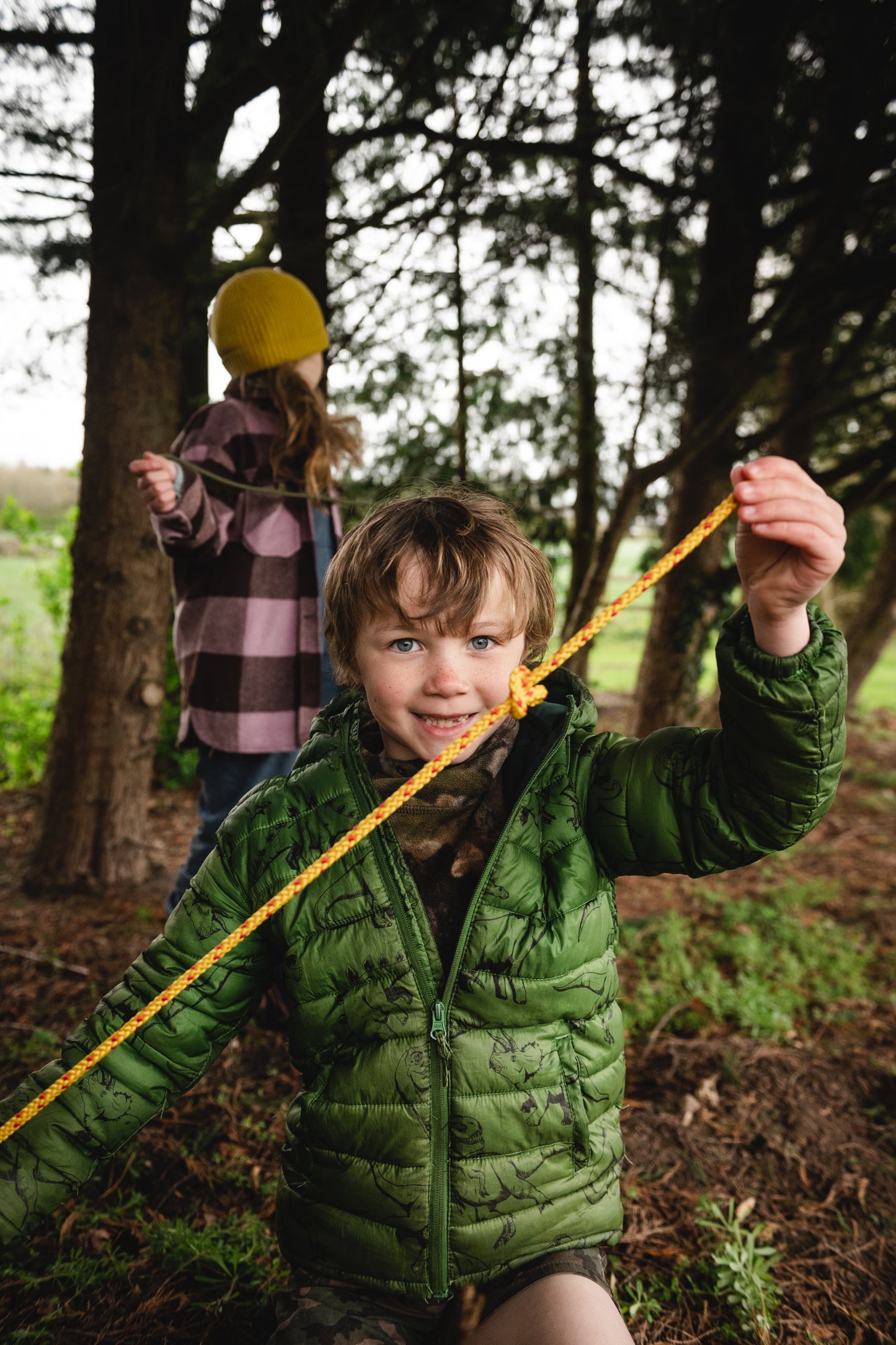 Shows a child proudly holding up one of the knots he has made on the yellow and red cordage.