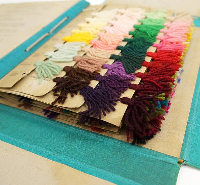 Color swatch book with colorful yarn samples on a wooden board