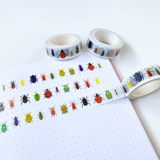 British Beetles Washi Tape unrolled on a craft project, showcasing its low-tack adhesive and vibrant watercolour insect designs. Made in UK.