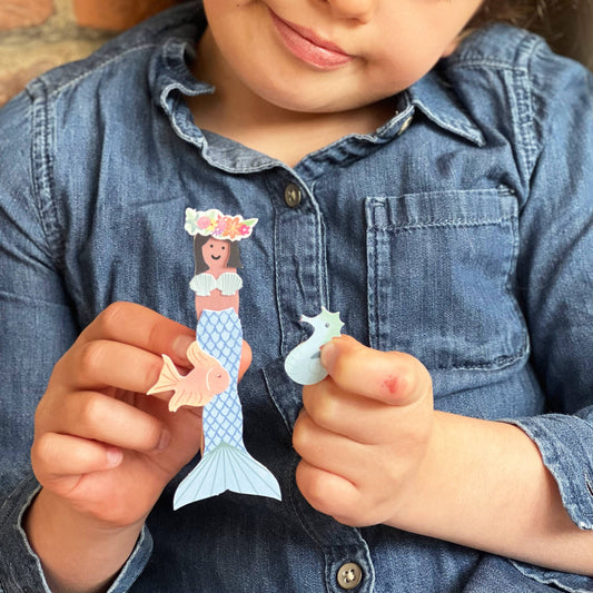 Child's hands assembling the mermaid peg doll, showing various customisation options
