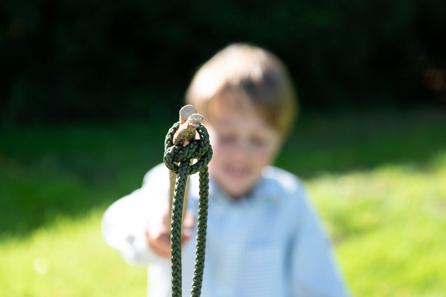 Image of a child holding up one of the knots on the end of a stick.