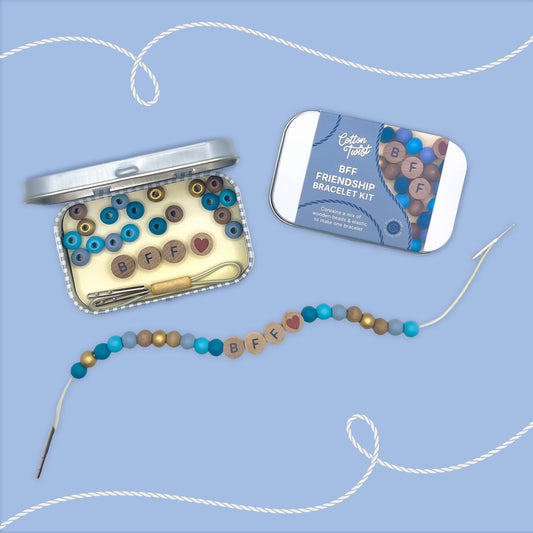 Two finished BFF friendship bracelets from the Cotton Twist kit, showcasing rainbow and blue wooden beads, next to the open tin.