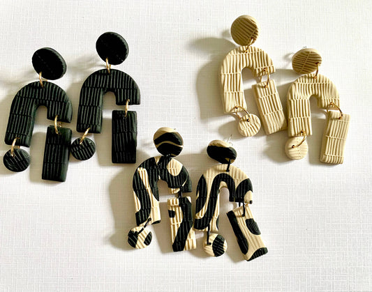 Detailed shot of Interwoven beige and black polymer clay earrings.