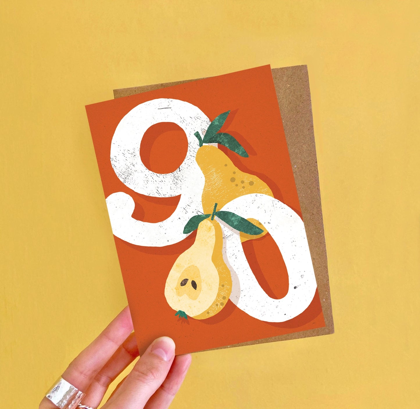 A6 birthday card featuring a bright pear-themed illustration and ‘Ninety’ caption by Emily Nash, printed on premium matte card with recycled kraft envelope.