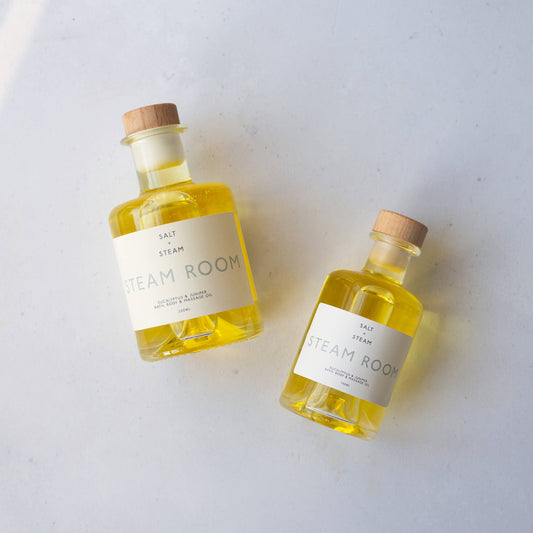 Hand applying Steam Room Eucalyptus & Juniper Bath & Body Oil onto skin, showing hydration