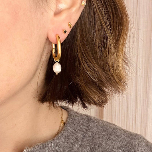 Close-up of Little Nell gold-plated oval hoop earrings with pearl charm, highlighting the quality and design.