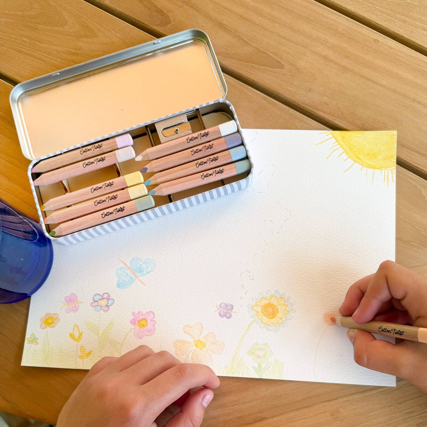 Colouring book with pencils and a tin on a wooden table