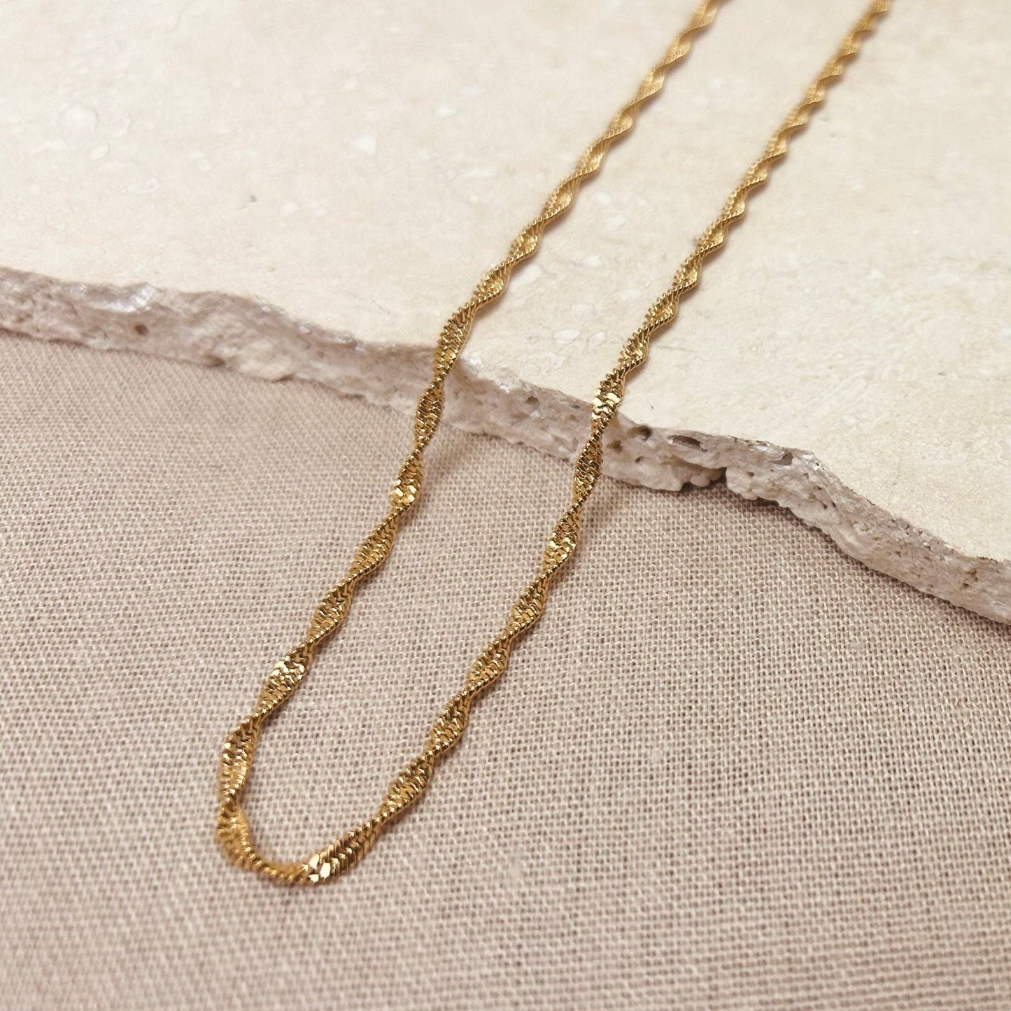 Silver twisted chain necklace styled casually on a flat lay
