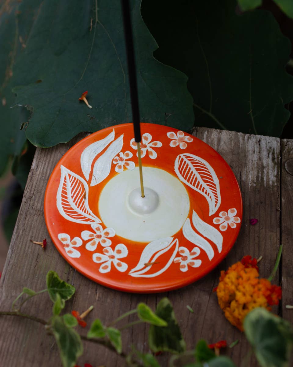 Round soapstone incense holder with hand painted orange floral design, crafted in Kisii, Kenya from sustainable stone and finished with beeswax.