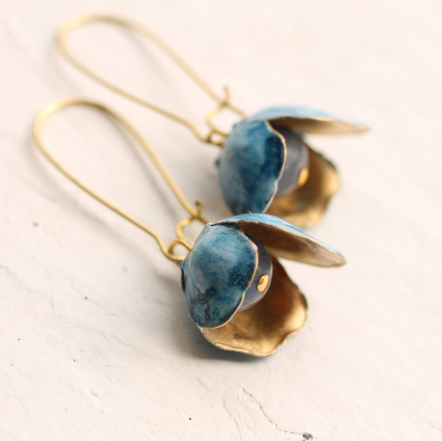 These unusual and beautiful bluebell earrings are made from vintage glass beads, layered with golden brass petals. The brass has flecks of rich blue and white paint which pick out the delicate blue of the bead underneath. The earrings are made of vintage glass and solid brass wire, and measure exactly two inches (5cm) in length.