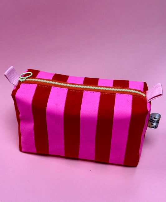 Pink and red stripe wax cotton pouch, open to show contrasting lining and spacious interior.