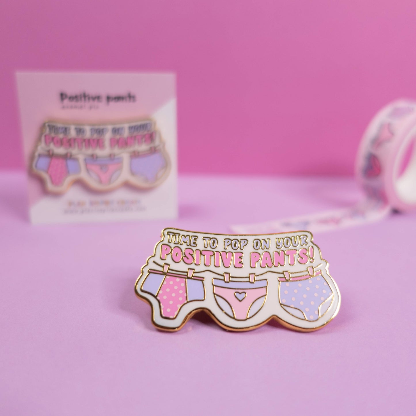 Positive Pants gold pin attached to a jacket lapel