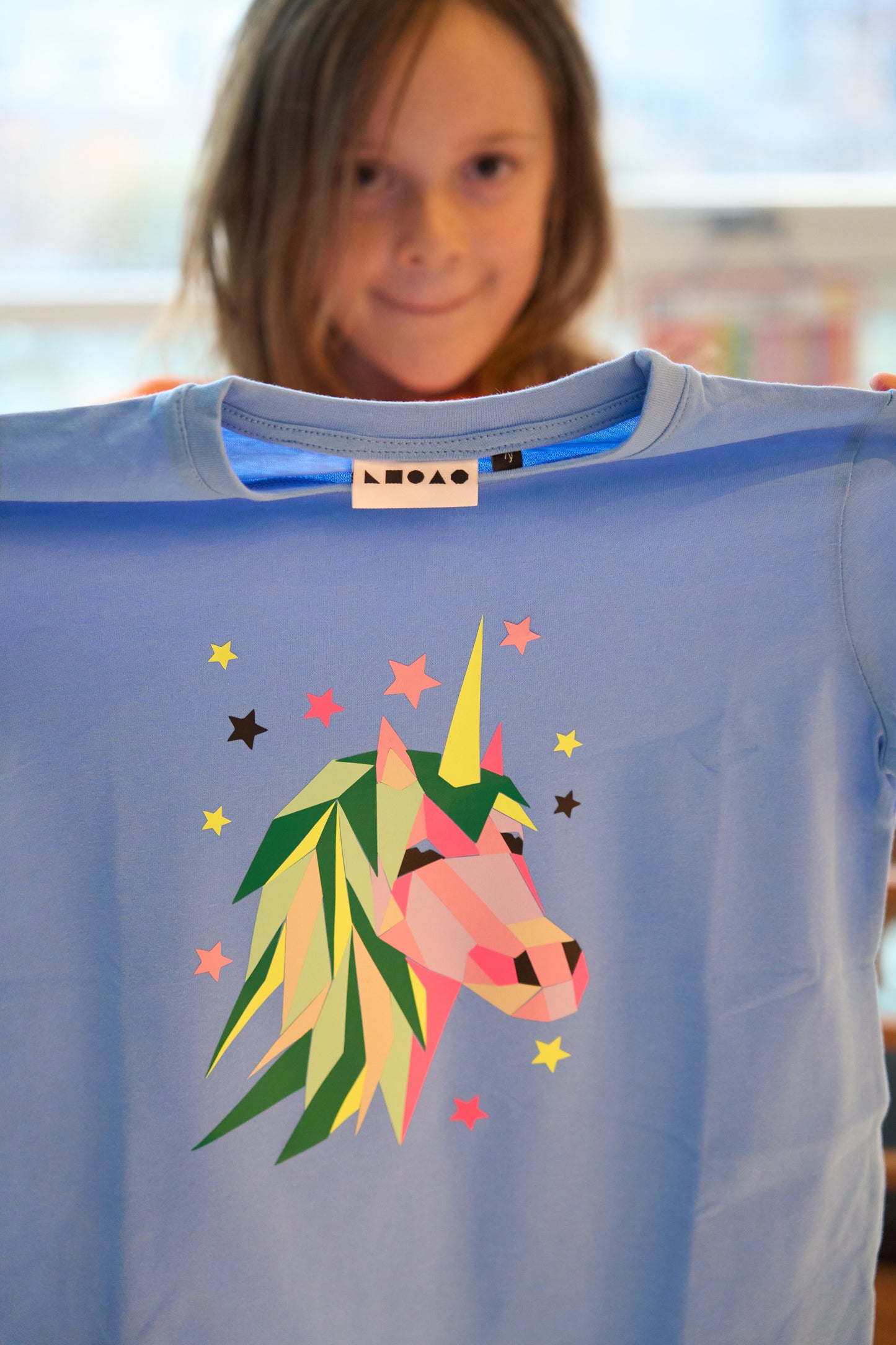 A child shows her finished creation of a Unicorn peel off and print Popkit on her tshirt.