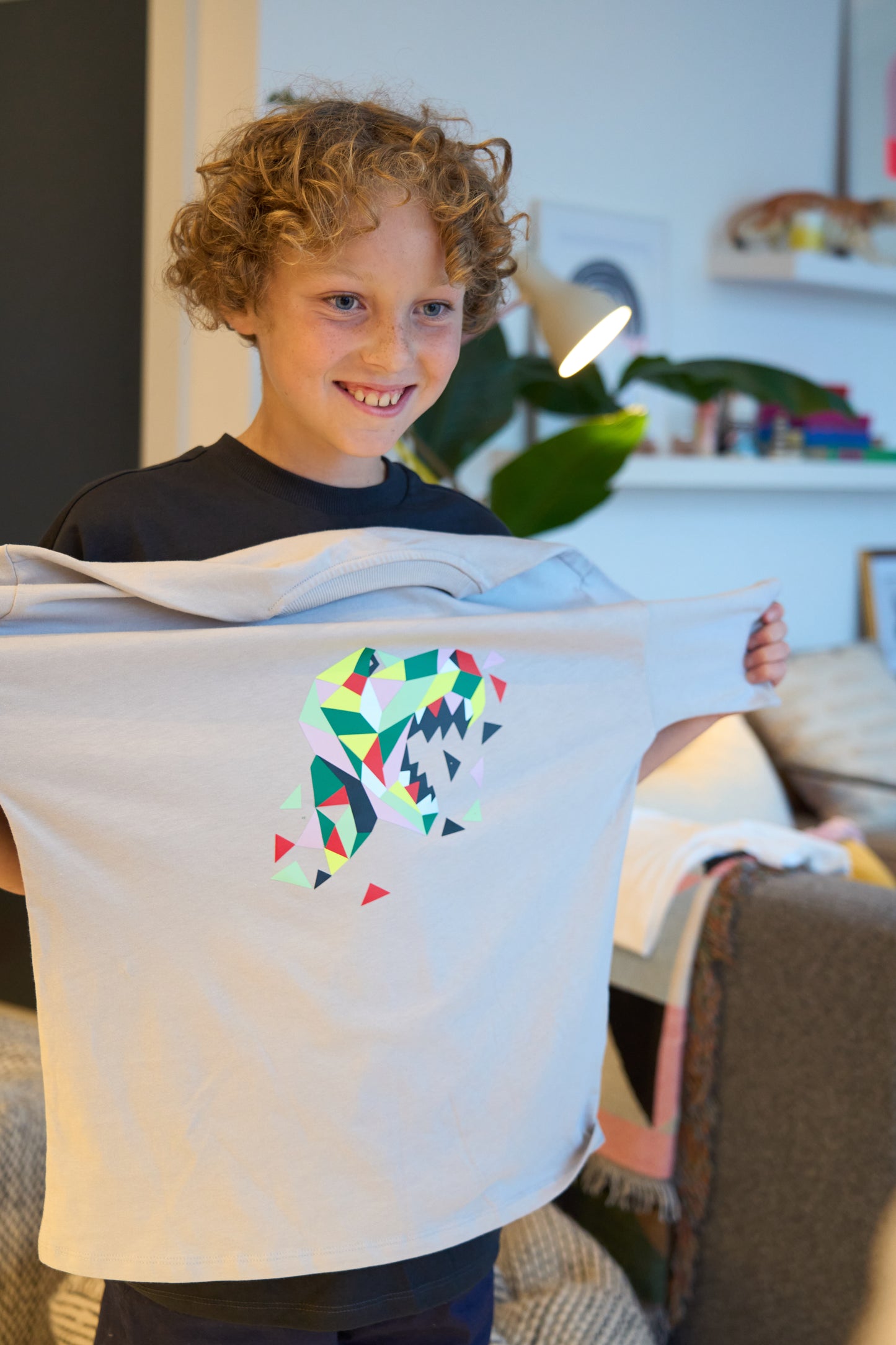 Proud child showcasing a grey t-shirt with the completed Dinosaur POPKIT design.