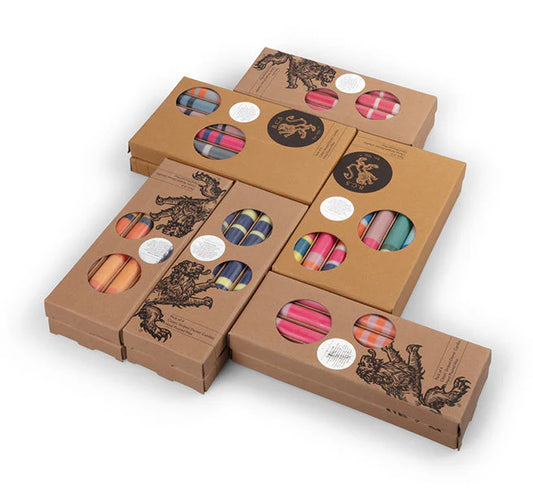 Assortment of British Colour Standard striped dinner candles in various colours, displayed in their eco-friendly packaging.