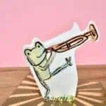 Eco-friendly die-cut birthday card featuring a frog playing trumpet