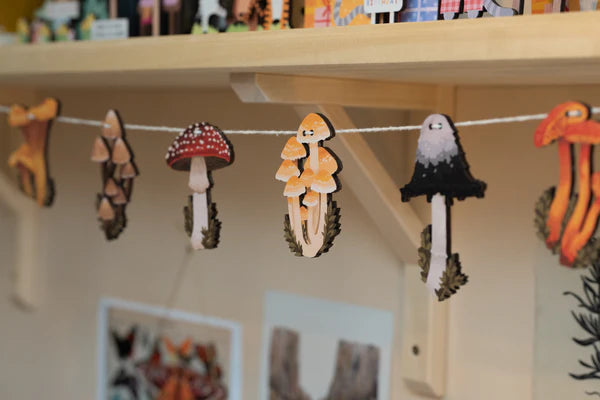 Hand designed Mushrooms of the British Isles garland, perfect for decorating your home or workspace. Perfect for nature lovers or toadstool enthusiasts. Made from sustainably sourced maple wood.
Made in Dapple & Dot's New Forest studio, from the illustration, to the laser cutting, to the printing to the packing.
EACH PRODUCT INCLUDES: 1 x pop out wooden sheet, 2 metres of cotton twine, 1 x labelled kraft envelope as packaging.