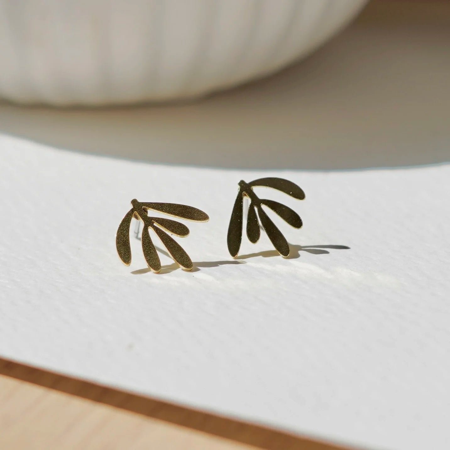 Delicate botanical brass leaf stud earrings from Copper Bee, hypoallergenic stainless steel posts, intricate laser-cut design, lightweight handmade UK jewellery.