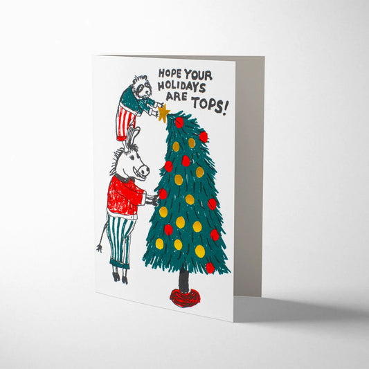 Tops Holiday Tree Animals Christmas card by Egg Press, cartoon raccoon standing on donkey's shoulders placing star on tree, letterpress printed, kraft envelope, sustainably certified paper, 108mm x 140mm.