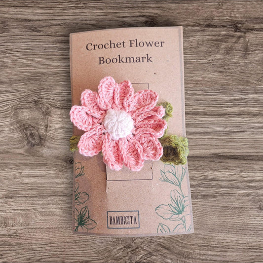 Crochet flower bookmark on a cardboard backing with 'Bambicta' branding, placed on a wooden surface.