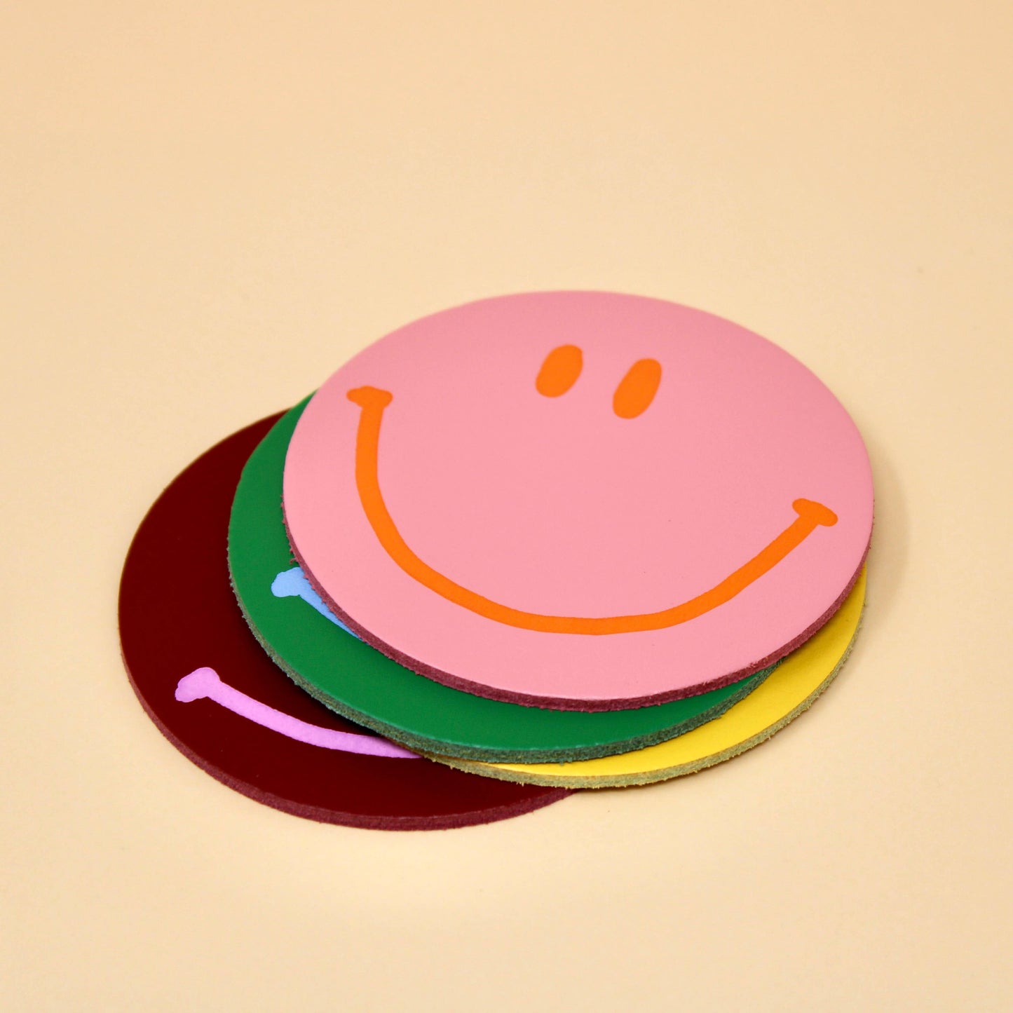 Happy Face Smilie Leather Coasters - Set of 4. Pink, Yellow, Green and Burgundy. Designed and made in the UK.