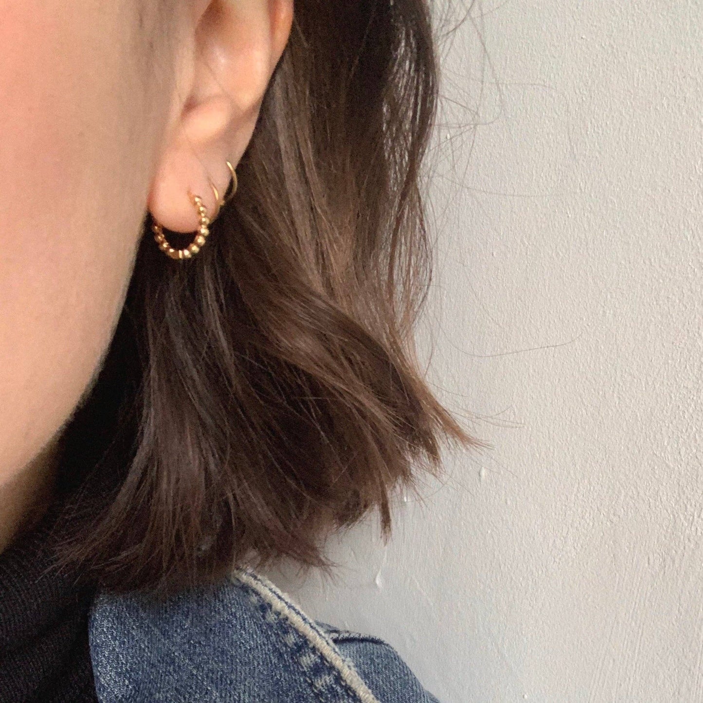 Close-up of gold plated hinged bubble hoop earrings showing texture