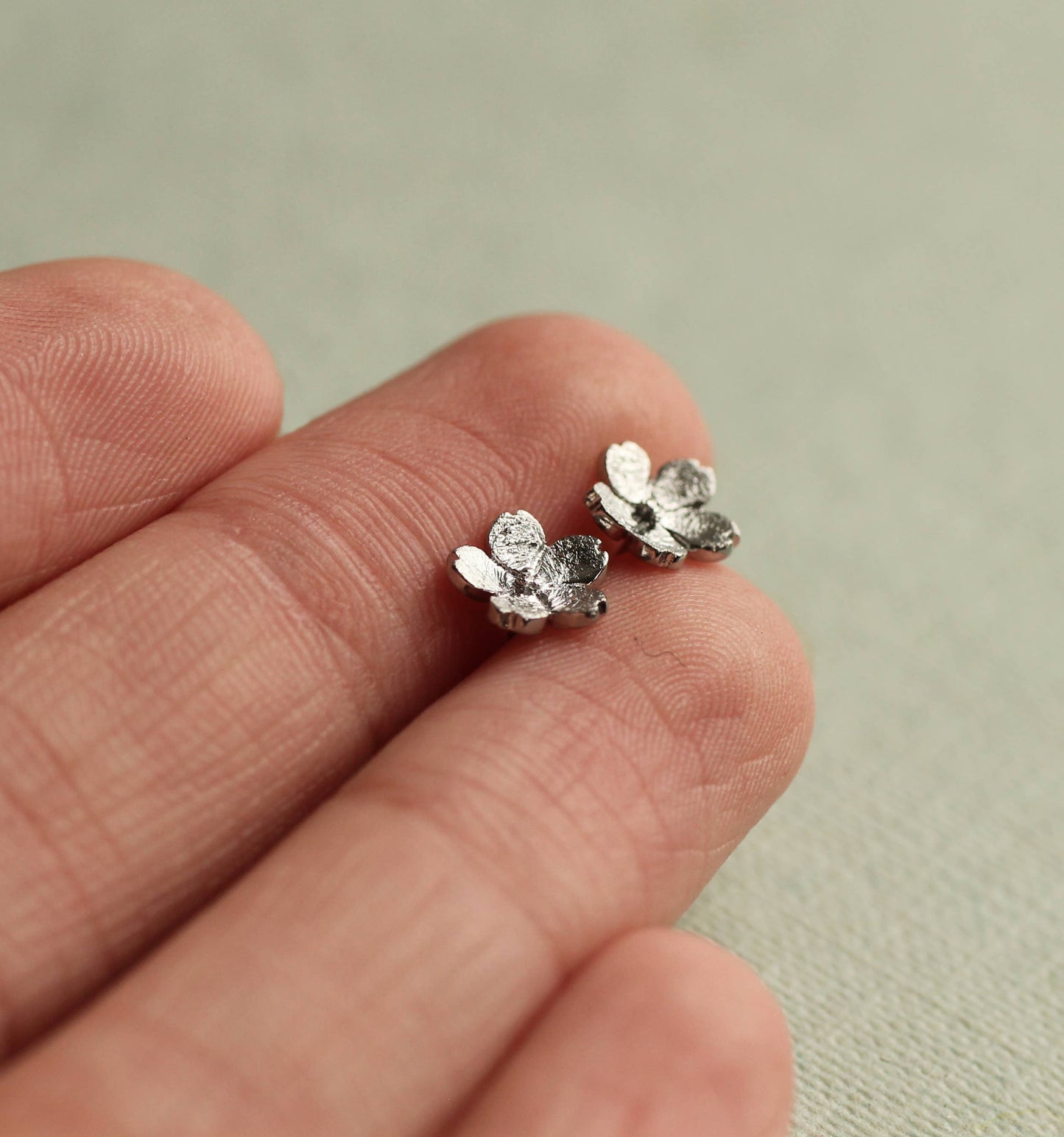 These sweet and dainty stud earrings feature a pair of tiny forget me not flowers, made from Sterling Silver with a subtle brushed texture. The earrings measure 9mm in diameter.