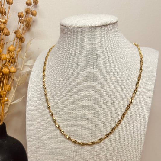 Model wearing a silver twisted chain necklace, layered with other jewellery