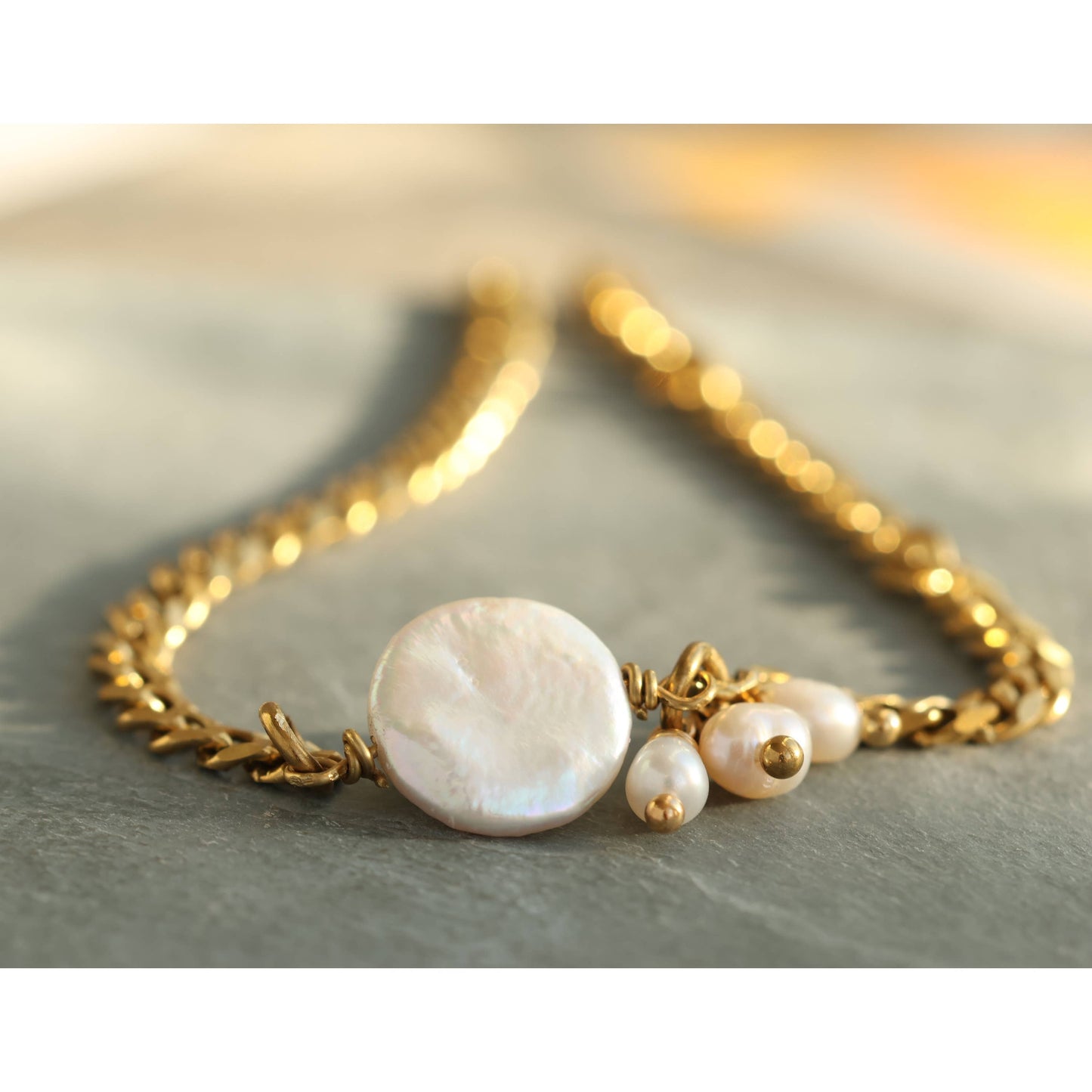 Detail shot of gold figaro chain and pearl cluster on the bracelet