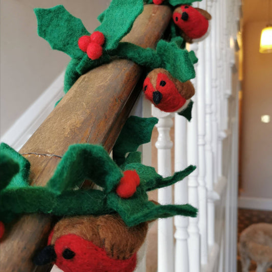 Full length view of a handmade felt holly garland with robins displayed as a festive decoration.