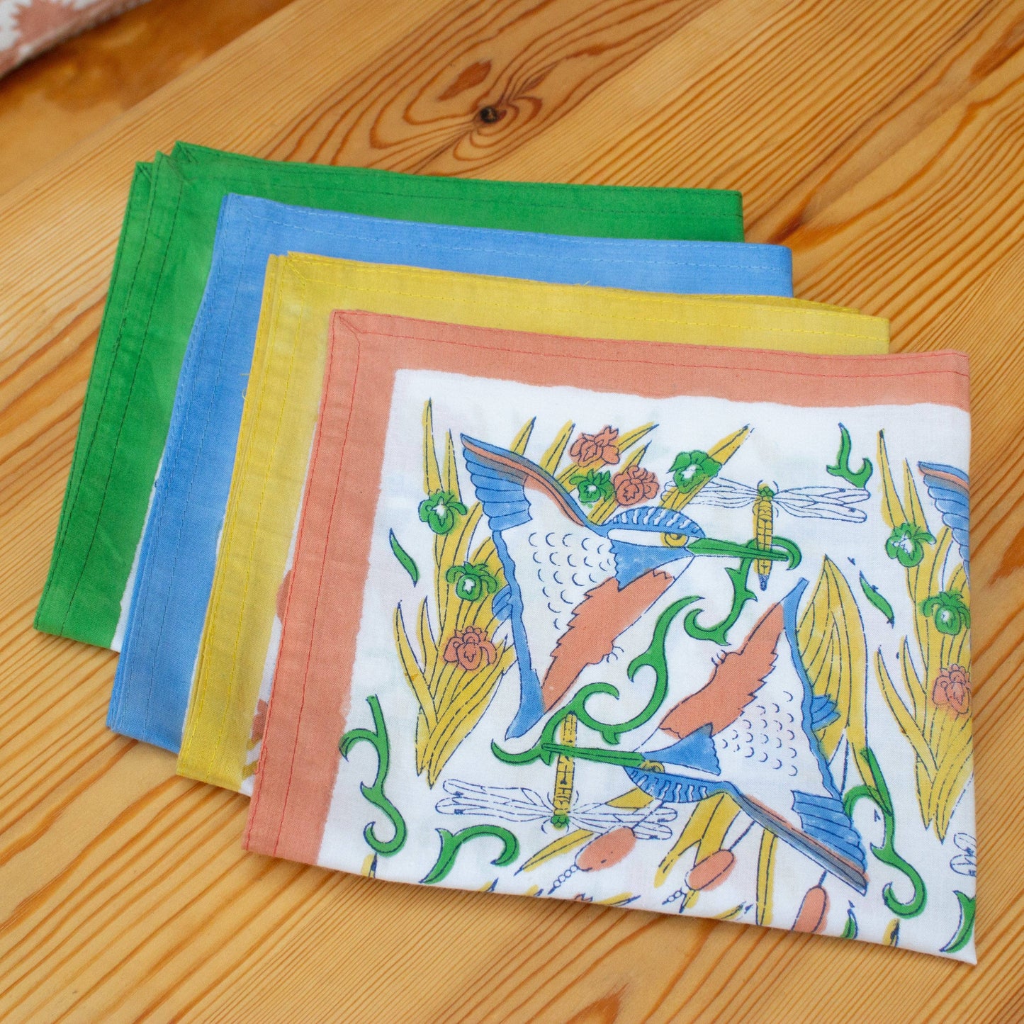 Hand wood block printed organic cotton napkins made in Jaipur, India. Add a touch of joy to your dining table with our beautiful set of four organic cotton napkins. Featuring AARVEN's signature 'Kingfisher' print. Block printed with different colourful borders (green, blue, coral and yellow) onto a white organic cotton background.