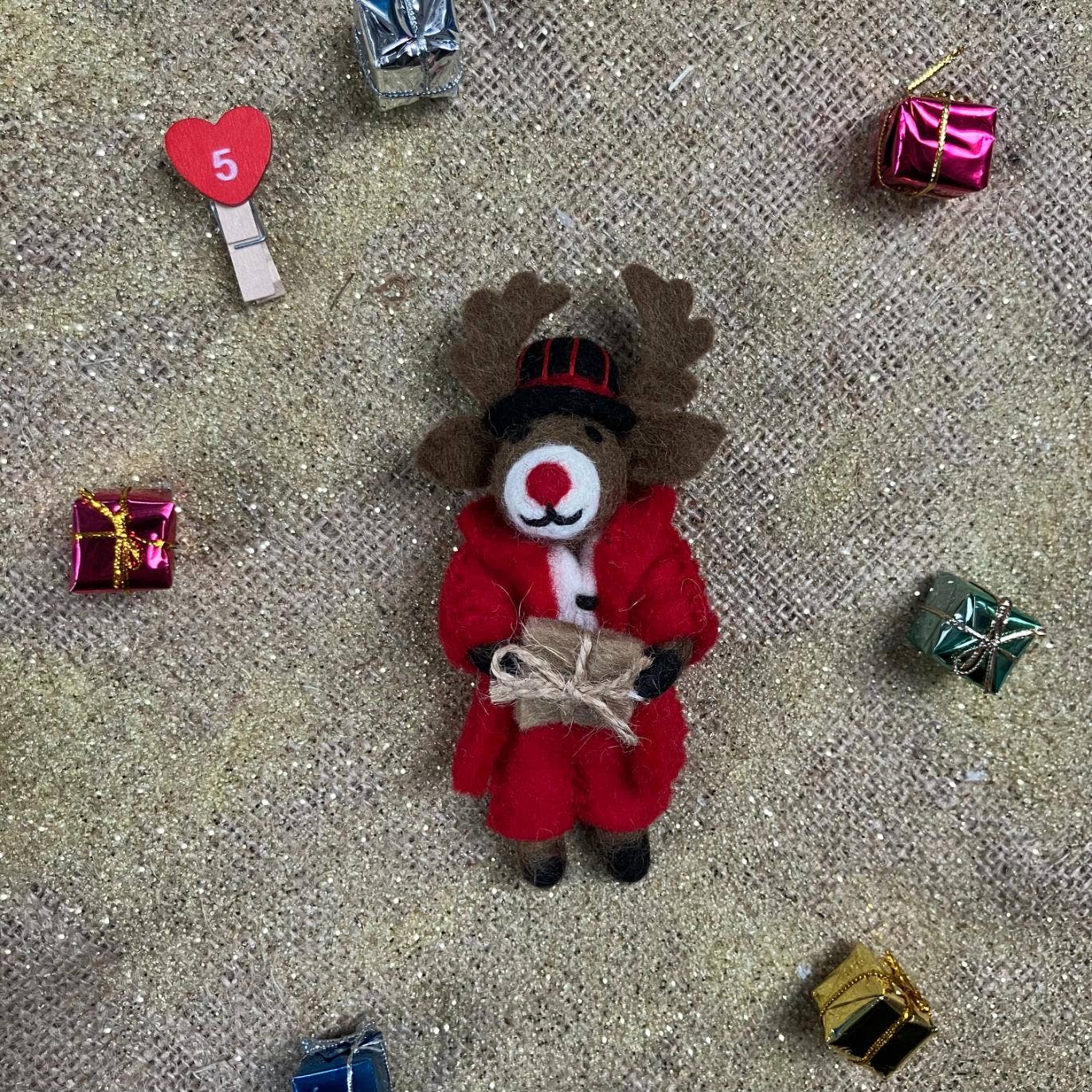 Handmade felt Dasher Christmas reindeer decoration by Felt So Good, sustainable wool with red suit, black fedora, and gift, fair trade and plastic-free