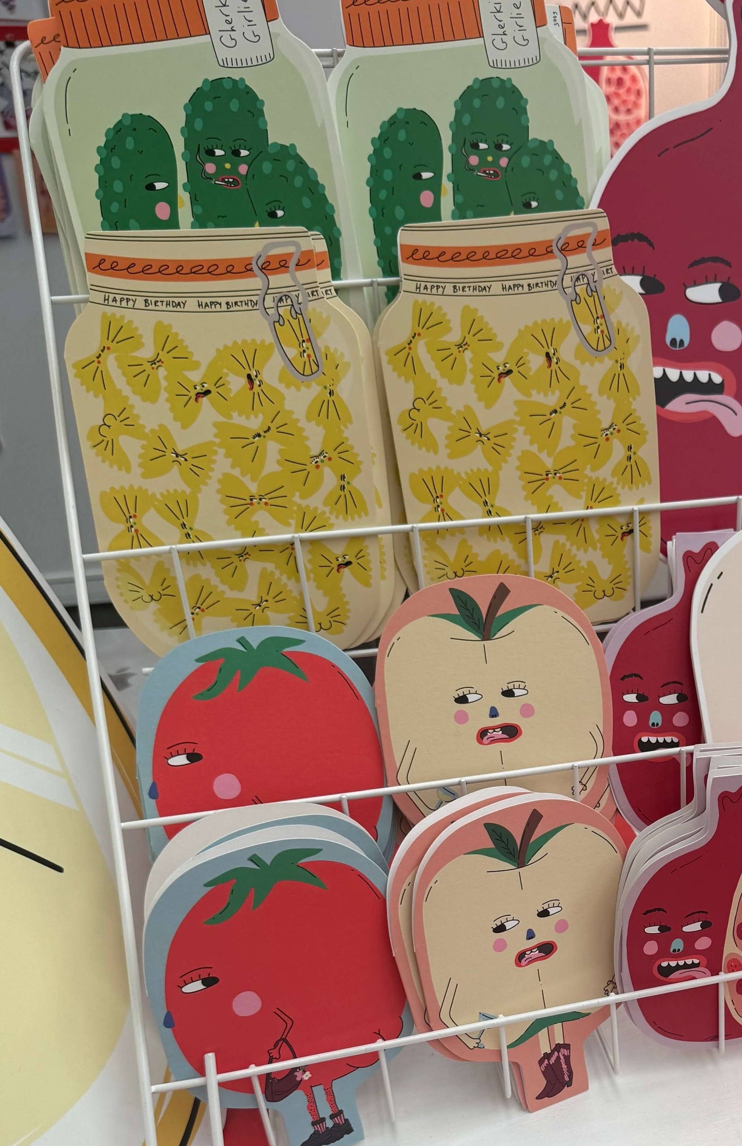 Display of colourful fruit with cartoon designs on a white rack.