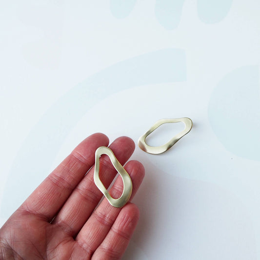 Wavy gold statement earrings showing sculptural design