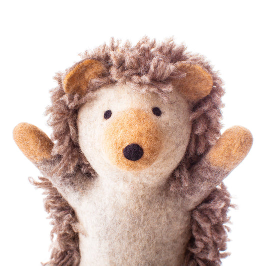 Child playing with Hilda Hedgehog organic wool puppet, close-up